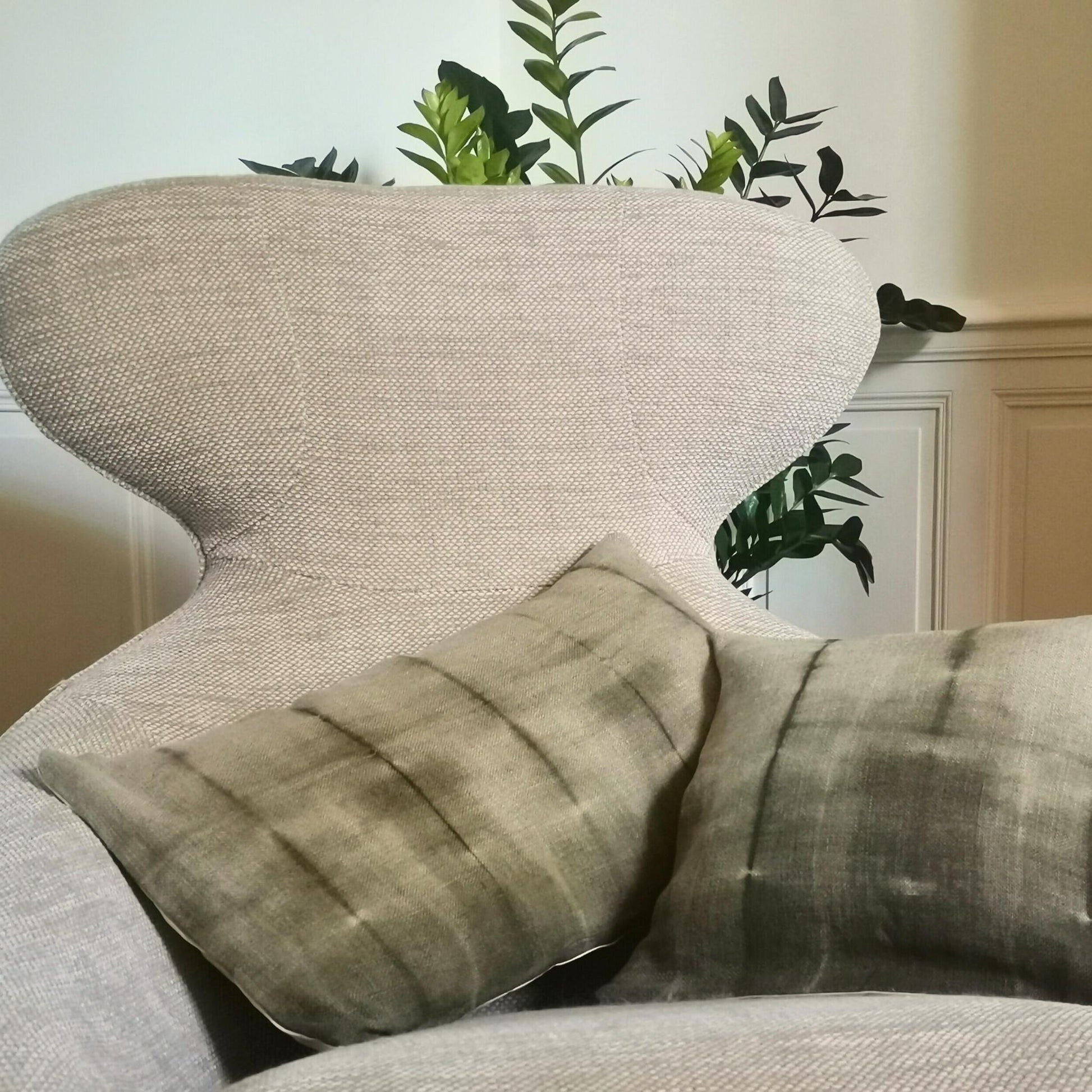 Duo de coussins en lin ancien, teints naturellement au mimosa avec un effet tie and dye subtil, présenté sur un fond neutre. Teintes douces sable et vert kaki, finition artisanale.