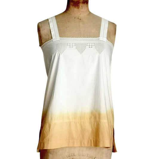 Top à bretelles en coton blanc avec broderies délicates sur le buste et un effet tie and dye beige en bas, affiché sur un buste de couture. Style bohème et intemporel.